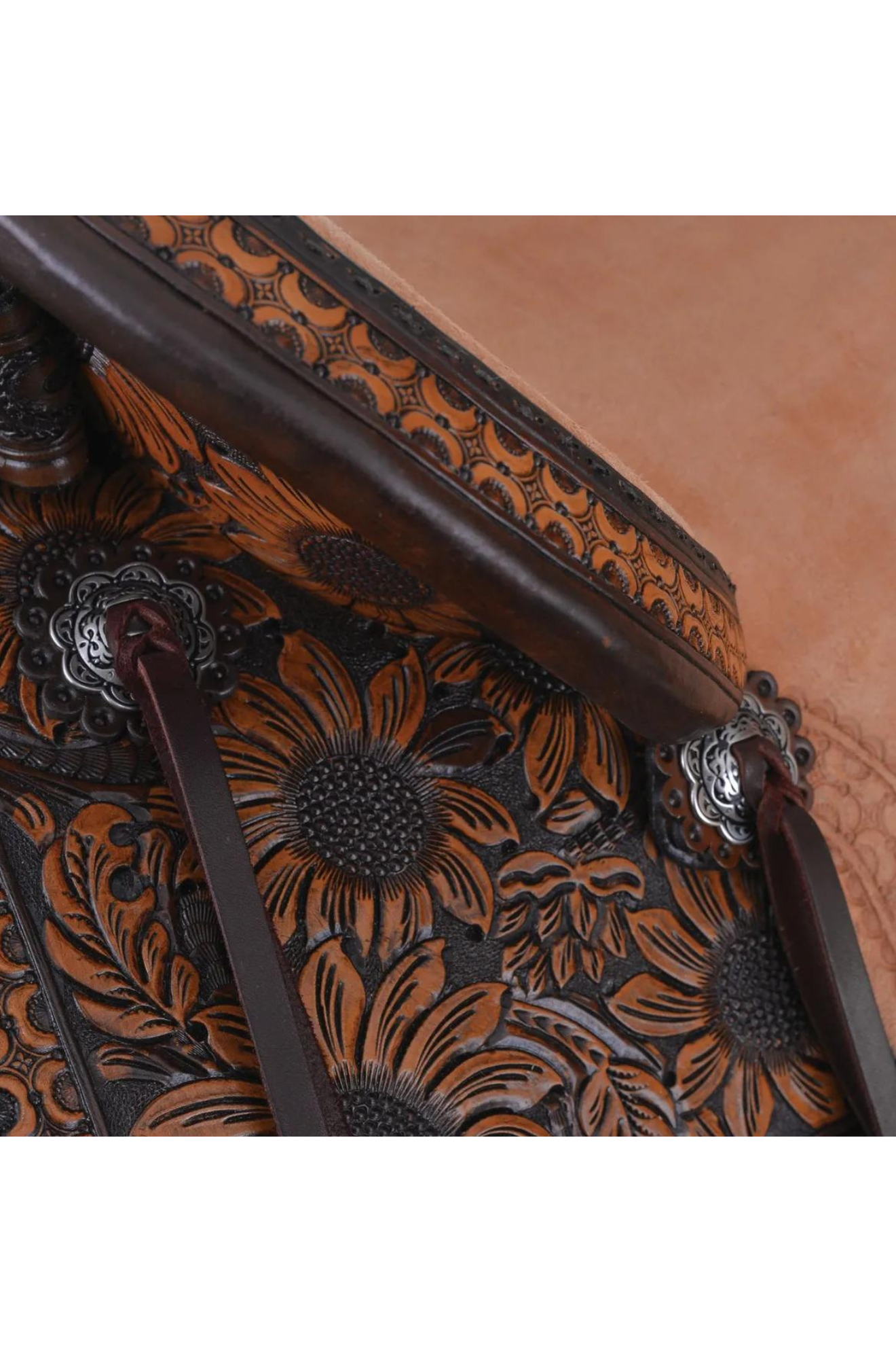 A brown western saddle with sunflower design and custom border tooling, including a matching flank cinch, made by Circle Y.
