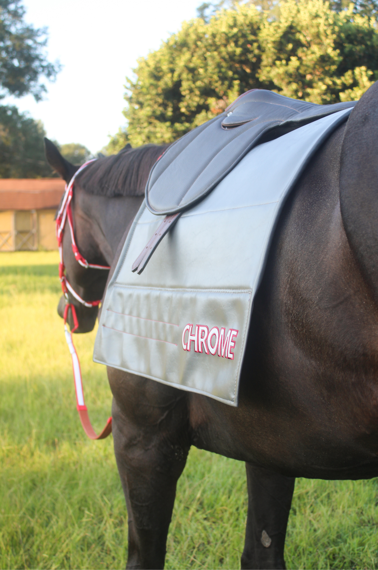 A gray custom embroidered saddle pad with pink embroidery on the sides.