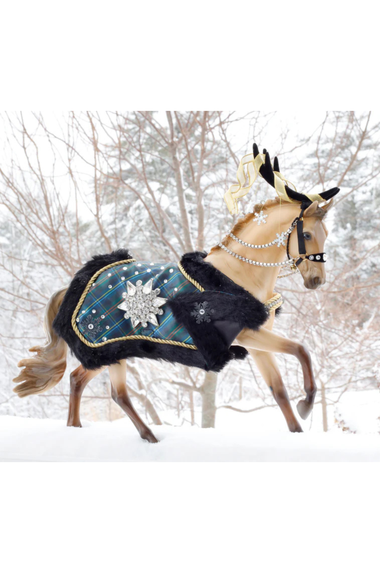A model horse with a warm golden buckskin coat, dressed in a black and silver plaid blanket with snowflake patterns and gem-studded reins.