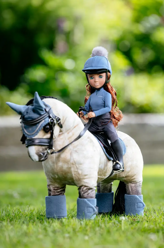 Barbie doll in equestrian outfit sitting on a horse with a blurred green background