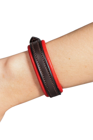Red and black leather bracelet on a wrist against a white background