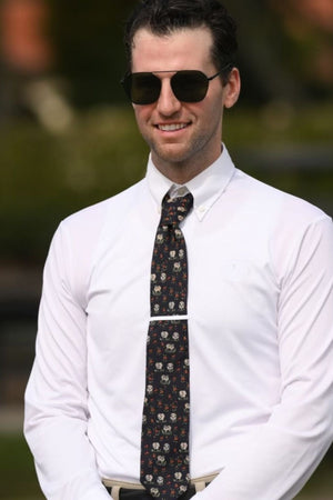 Man wearing a white shirt and patterned tie with sunglasses, outdoors.