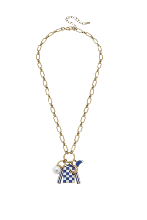 A necklace with a gold-tone chain, featuring a blue and white checkerboard jockey silks charm, a pearl charm, and a gold horseshoe charm.
