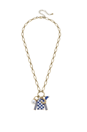 A necklace with a gold-tone chain, featuring a blue and white checkerboard jockey silks charm, a pearl charm, and a gold horseshoe charm.