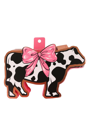 A bath sponge with a cow pattern and a pink bow.