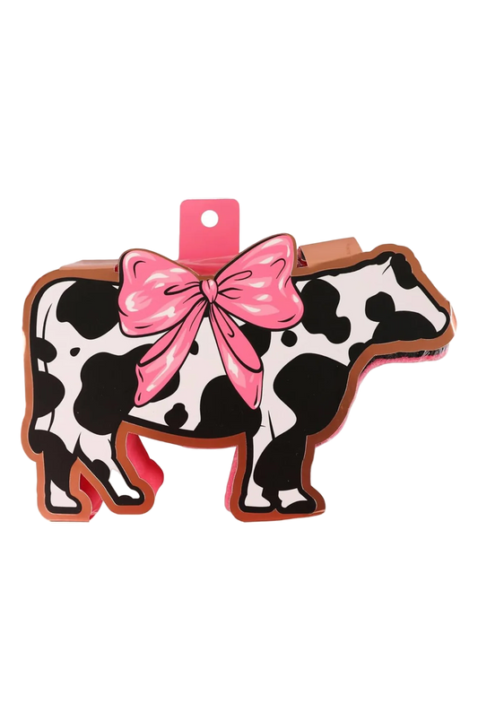 A bath sponge with a cow pattern and a pink bow.