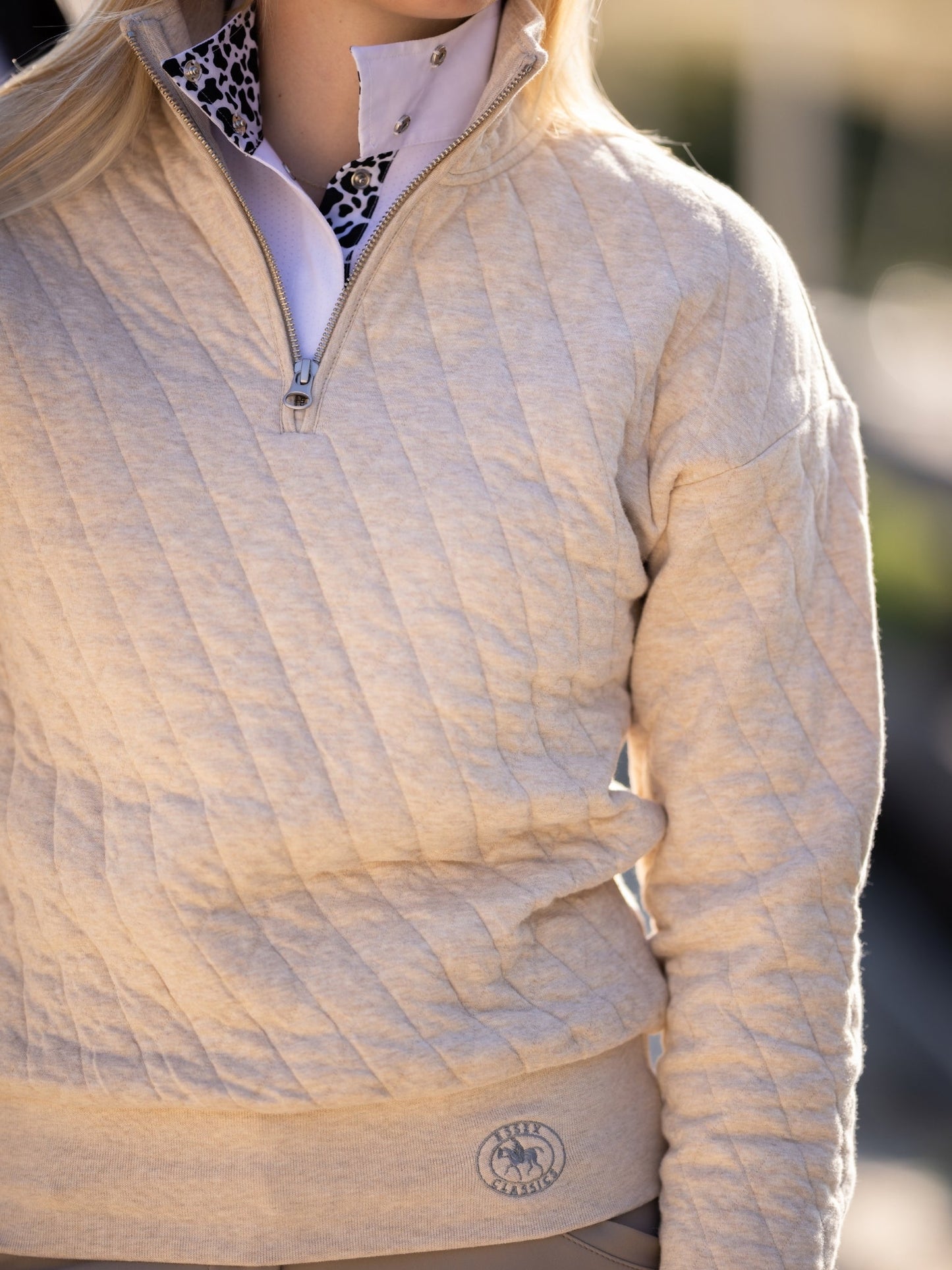 Close-up of a beige quilted jacket with a brand logo on a blurred background