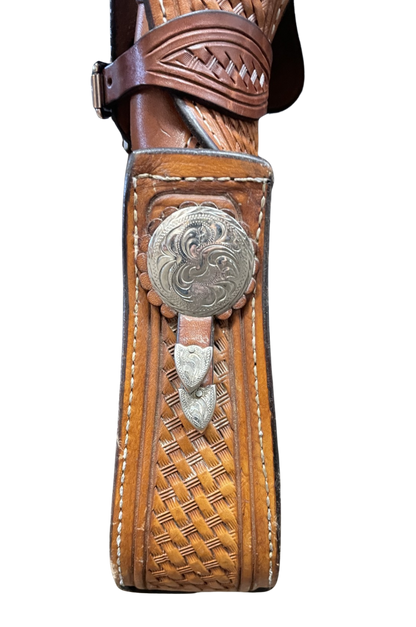Close-up of a brown leather gun holster with decorative metal concho on a white background