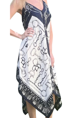 A woman viewed from the back wearing a multicolored scarf dress with a geometric pattern, paired with a denim jacket and a wide-brimmed hat.