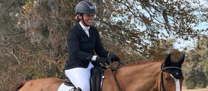 Person riding a horse in an outdoor setting with trees in the background