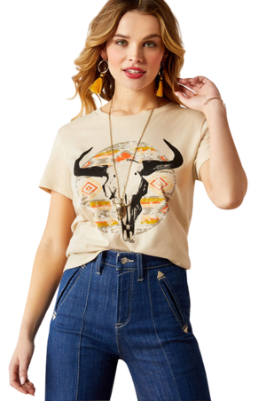 A woman wearing a beige t-shirt with a longhorn watercolor design, paired with blue jeans.
