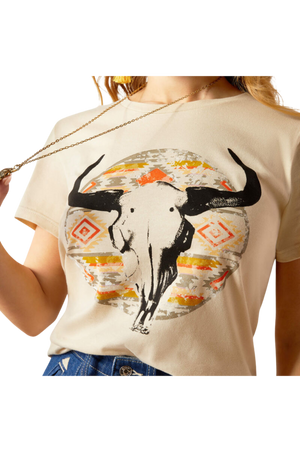 A woman wearing a beige t-shirt with a longhorn watercolor design, paired with blue jeans.