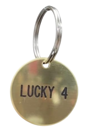 A round brass tag with the text 'LUCKY 4' engraved on it, attached to a keyring.