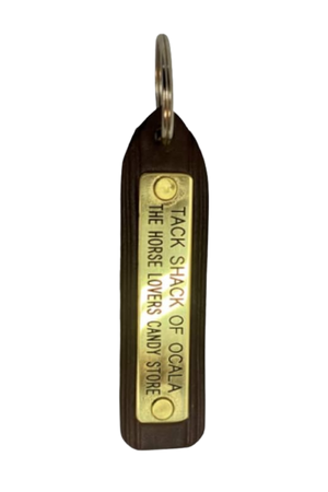 A custom leather key chain with a brass engraved plate, showing the store name and logo.