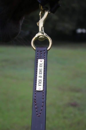 A black leather horse lead with a brass snap, coiled and displayed against a white background.