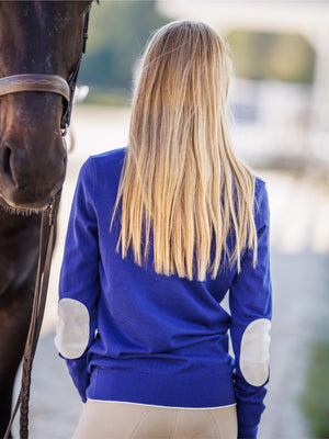Person wearing a blue equestrian shirt with a horse in the foreground