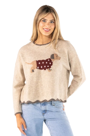 A woman wearing a beige knit sweater with a dachshund graphic wearing a burgundy polka-dot sweater, paired with light blue jeans, against a plain white background.