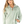 A woman wearing a sage green zip-up fleece jacket with a textured knit pattern, paired with light blue jeans, against a solid white background.
