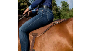 Person riding a horse wearing blue jeans with a visible brand logo.