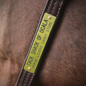Close-up of a horse bridle with a 'Shack of Ocala' label on a brown horse.