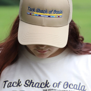 Person wearing a beige cap with 'Tack Shack of Ocala' branding, looking down.