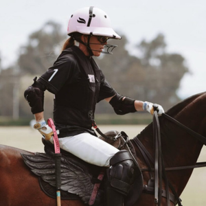 Person riding a horse in equestrian gear with a helmet and gloves.