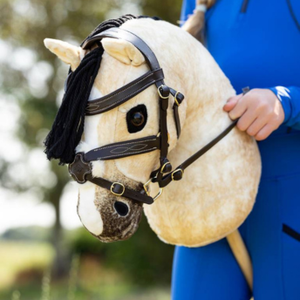 Close-up of a horse headstall with a person in a blue outfit holding it.
