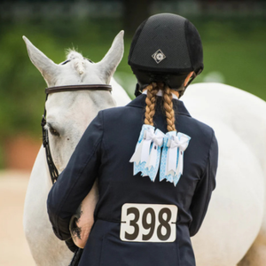 Person in equestrian attire with a white horse, wearing a helmet and a jacket with number 398.