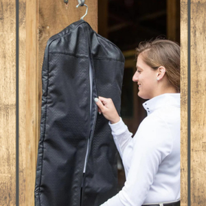 Woman holding a black garment bag against a wooden background
