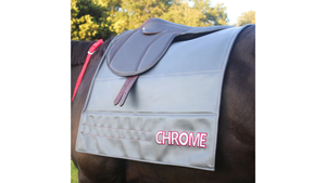 Horse wearing a gray saddle pad with 'Chrome' branding
