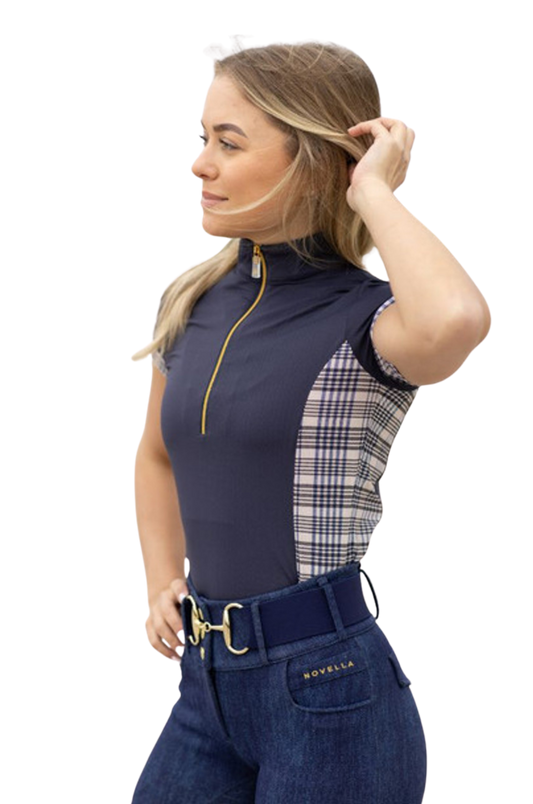 Woman wearing a navy equestrian top with plaid accents and jeans on a white background