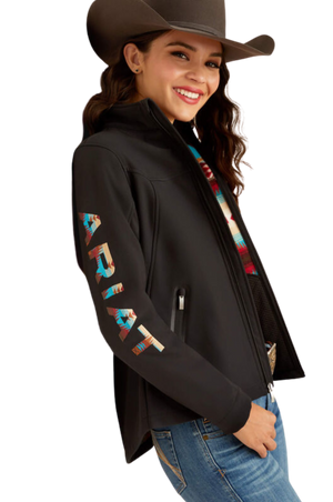 A woman wearing a black softshell jacket with the text 'TEAM' on the sleeves and a logo on the chest.