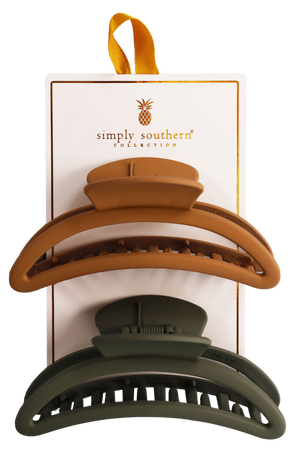 Two hair clips, one green and one brown, displayed on a vertical cardboard stand with a logo at the top.