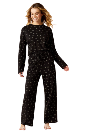 A woman wearing a beige pajama set with animal print patterns, standing against a solid background.