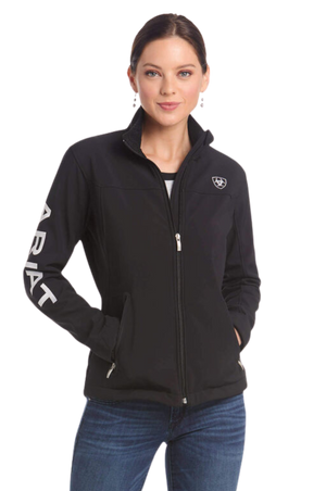A woman wearing a black softshell jacket with the text 'TEAM' on the sleeves and a logo on the chest.