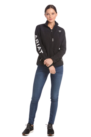 A woman wearing a black softshell jacket with the text 'TEAM' on the sleeves and a logo on the chest.