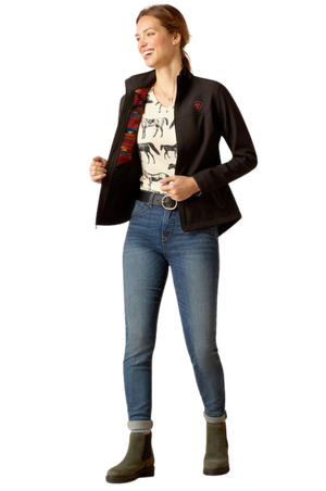 A woman wearing a black softshell jacket with the text 'TEAM' on the sleeves and a logo on the chest.