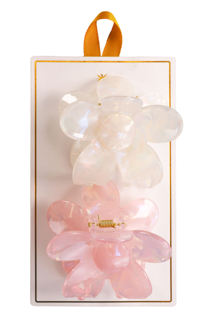 Two hair clips, one green and one brown, displayed on a vertical cardboard stand with a logo at the top.