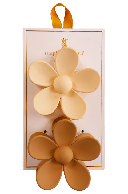 Two hair clips, one green and one brown, displayed on a vertical cardboard stand with a logo at the top.