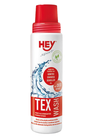 A bottle of HEY SPORT Tex Wash, a laundry detergent for waterproof clothing, with red cap and label showing a splash of water, indicating its use for cleaning.