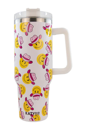 A white stainless steel tumbler with a handle, featuring a repeated pattern of happy faces wearing pink cowboy hats.