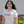 Person wearing a white t-shirt with text and graphics, standing outdoors.