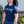 Woman wearing a blue t-shirt with text and graphics, standing outdoors.