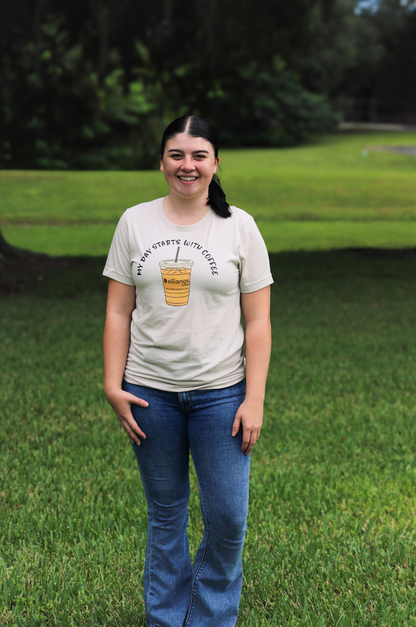Person wearing a t-shirt with a graphic design standing in a grassy area.