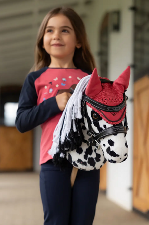 Young girl holding a small horse plush toy in an indoor setting