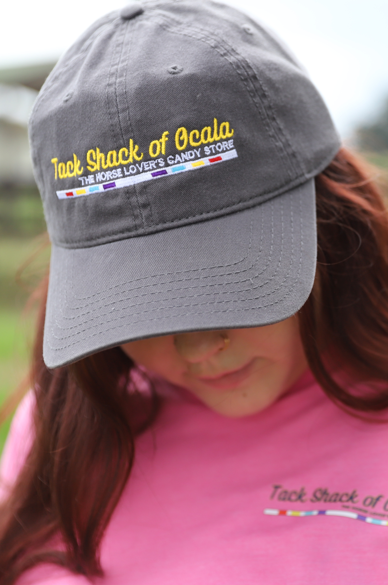 Person wearing a gray cap with 'Tack Shack of Ocala' branding, blurred background