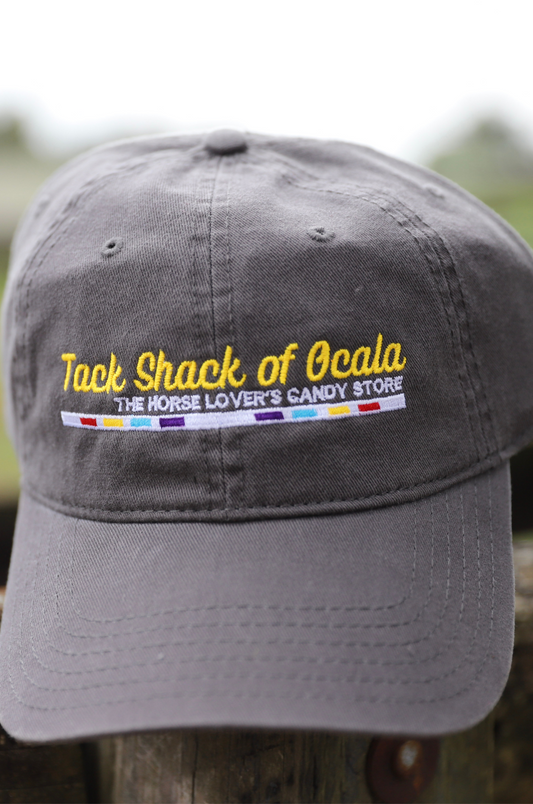 Gray cap with 'Tack Shack of Ocala' logo on a wooden post with a blurred background