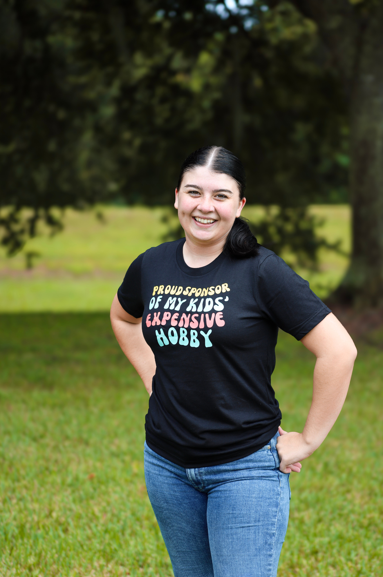 Person wearing a black t-shirt with colorful text in an outdoor setting