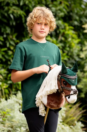 Young person holding a small horse with a green bridle in an outdoor setting
