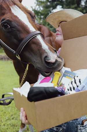 Person holding a box with a horse sniffing the contents outdoors
